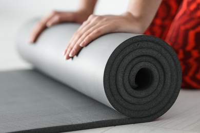 Young woman rolling yoga mat, closeup of hands