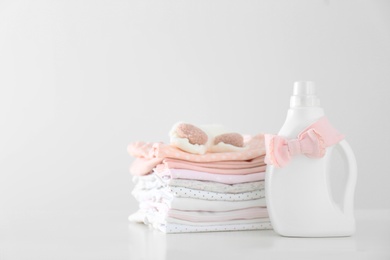 Detergent and children's clothes on white table