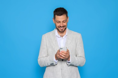 Happy man with smartphone on light blue background