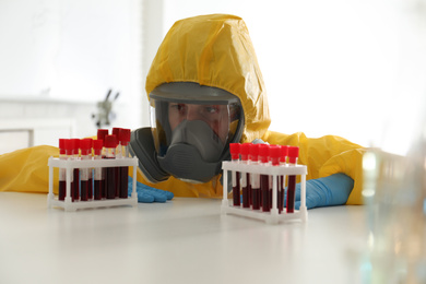 Scientist in chemical protective suit working with blood samples at laboratory. Virus research