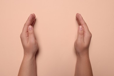 Woman holding on pale pink background, closeup of hands. Space for text