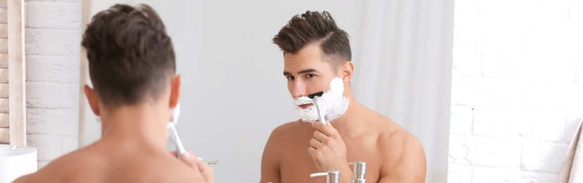 Young man shaving near mirror in bathroom. Banner design