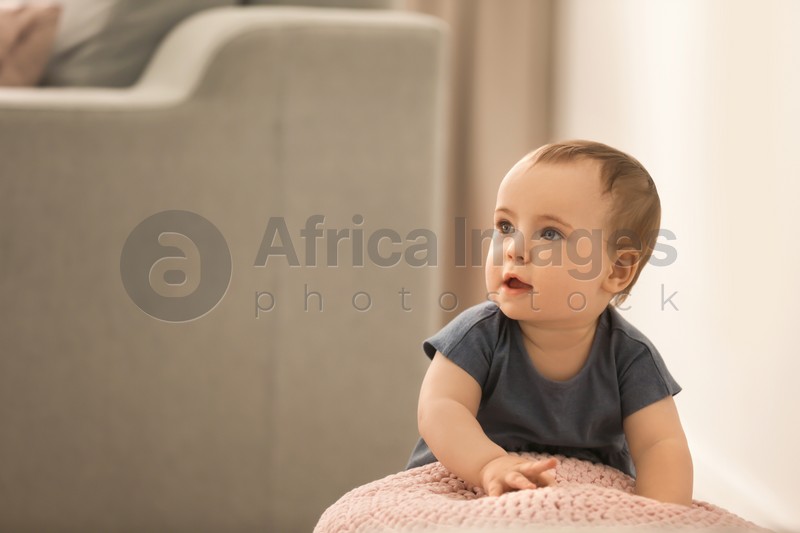 Photo of Cute baby holding on to pouf in living room. Learning to walk