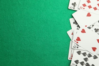 Photo of Scattered playing cards on green table, top view. Space for text