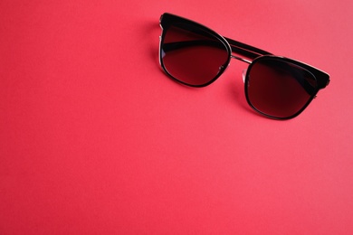 Stylish sunglasses on pink background, top view. Space for text