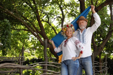 Photo of Happy mature couple with national flag of Ukraine outdoors