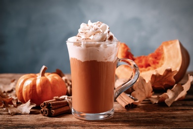 Delicious pumpkin latte and cinnamon on wooden table, closeup