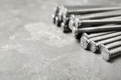 Photo of Many metal nails on grey background, closeup. Space for text