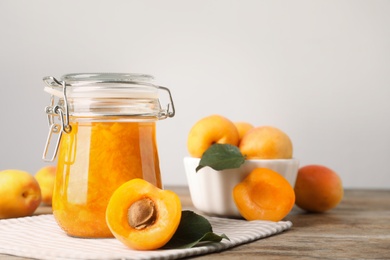 Jar of apricot jam and fresh fruits on wooden table