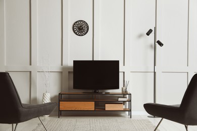 Photo of Elegant room interior with modern TV on stand and armchairs