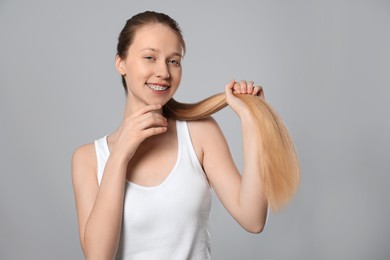Teenage girl with strong healthy hair on light grey background