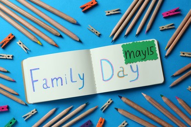 Happy International Family Day. Flat lay composition with notebook and stationery on light blue background