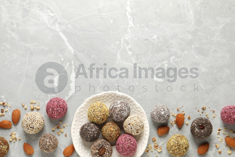 Delicious vegan candy balls and nuts on light grey marble table, flat lay. Space for text