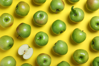 Tasty green apples on yellow background, flat lay