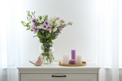 Bouquet of beautiful Eustoma flowers on chest of drawers in room. Space for text
