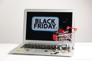Laptop and small cart on white table. Black Friday Sale online