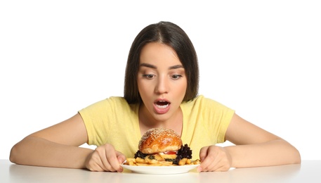 Concept of choice. Emotional woman with tasty burger and French fries on white background