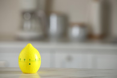 Kitchen timer in shape of lemon on white marble table against blurred background. Space for text