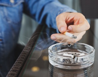 Photo of Man smoking cigarette at table in outdoor cafe, closeup