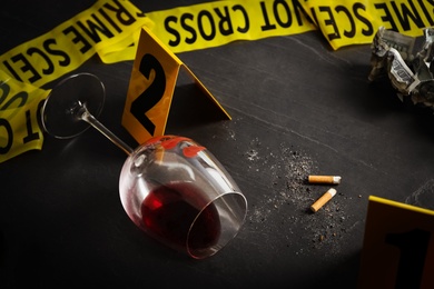 Wine glass with fingerprints and stubs on black slate table. Crime scene
