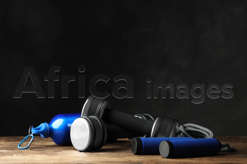 Gym equipment and accessories on floor against dark background. Space for text