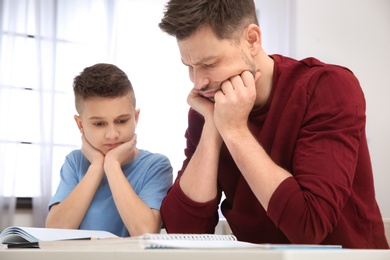 Dad helping his son with difficult homework assignment in room