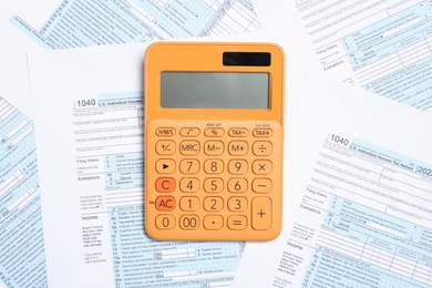 Orange calculator on documents, top view. Tax accounting