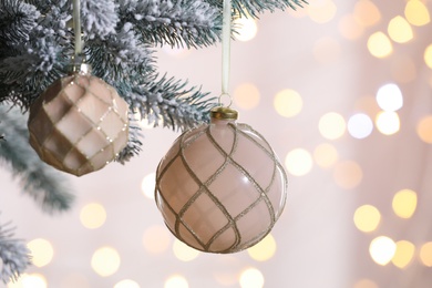 Christmas tree decorated with holiday baubles against blurred lights, closeup