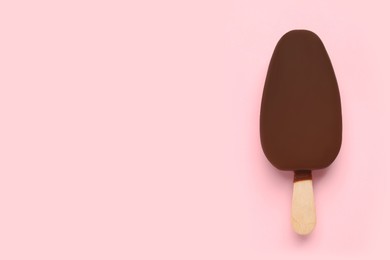 Ice cream glazed in chocolate on pink background, top view. Space for text