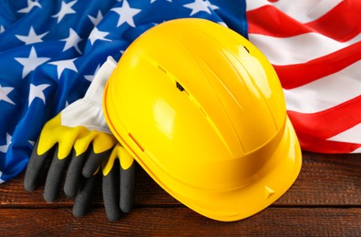 Yellow hard hat, gloves and American flag on wooden table