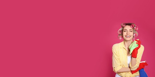 Young housewife with detergent and rag on pink background. Space for text