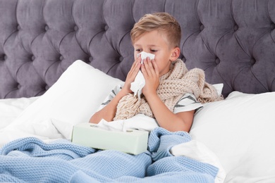 Ill boy suffering from cough in bed at home