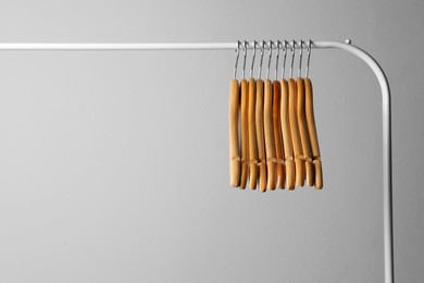 Photo of Wooden clothes hangers on metal rack against light grey background