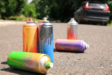 Used cans of spray paint on asphalt road. Graffiti supplies