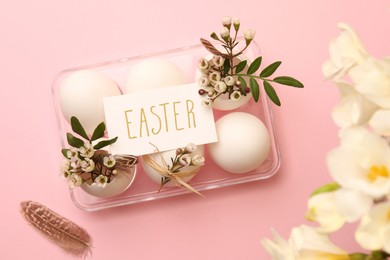 Photo of Flat lay composition with chicken eggs, floral decor and word Easter on pink background. Happy celebration