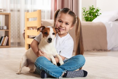 Photo of Cute girl hugging her dog on floor at home. Adorable pet
