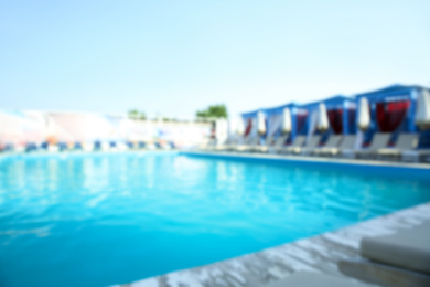 Blurred view of modern outdoor swimming pool on sunny day