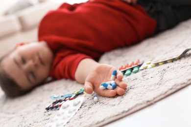 Unconscious little child with pills lying on floor at home. Household danger
