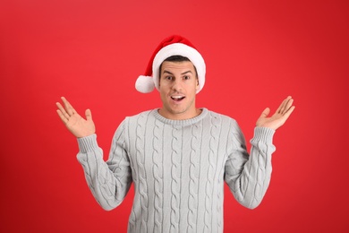 Surprised man wearing Santa hat on red background