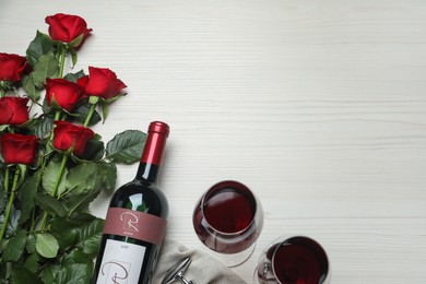Photo of Bottle and glasses of red wine with beautiful roses on white wooden table, flat lay. Space for text