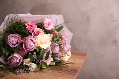Photo of Beautiful bouquet with roses on wooden table. Space for text