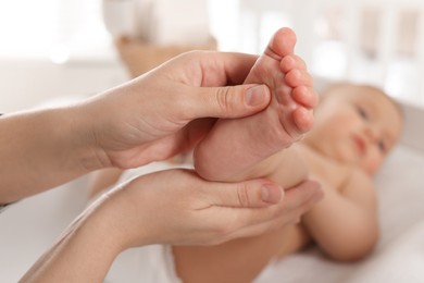 Mother massaging her cute baby with oil at home, closeup