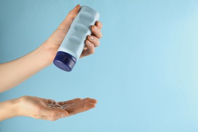 Photo of Woman applying dusting powder on light blue background, closeup. Space for text