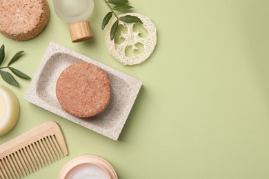 Flat lay composition of solid shampoo bars, loofah and comb on green background. Space for text