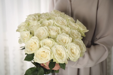 Woman holding luxury bouquet of fresh roses indoors, closeup