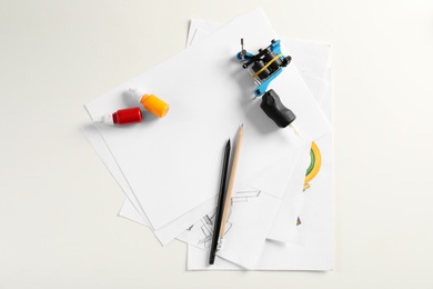 Composition with sheets of paper and tattoo machine on white background, top view