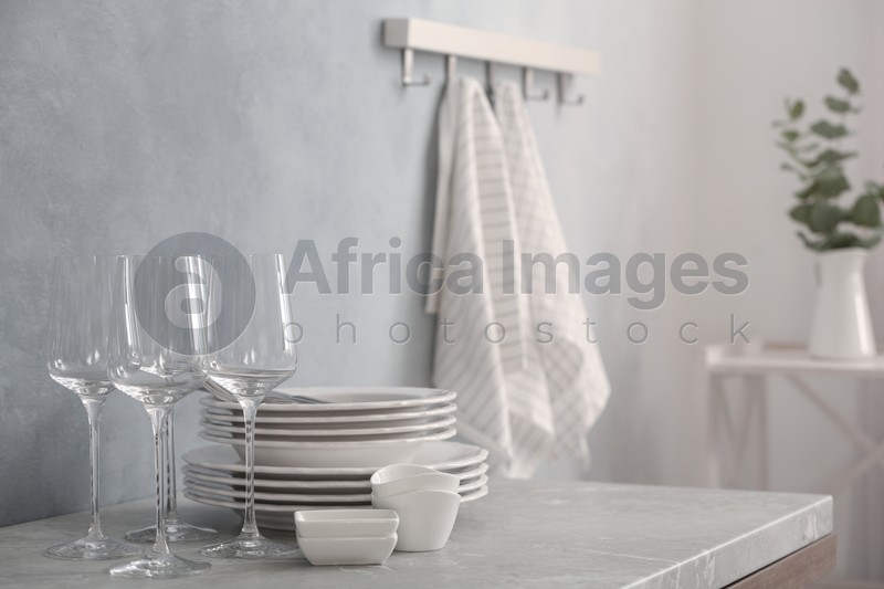 Photo of Set of clean dishware and wineglasses on grey table indoors. Space for text