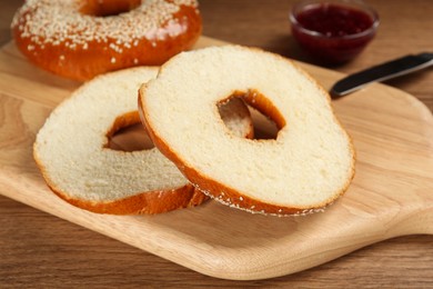 Delicious fresh bagels with sesame seeds on wooden table, closeup