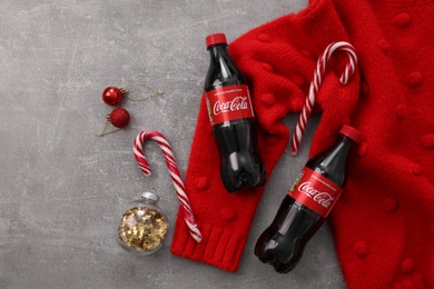 MYKOLAIV, UKRAINE - JANUARY 13, 2021: Flat lay composition with Coca-Cola bottles, Christmas decor and red sweater on floor