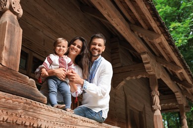Happy family in Ukrainian national clothes on wooden terrace